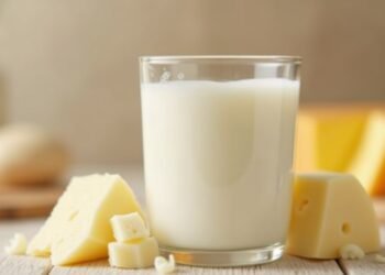A glass of whole milk surrounded by various dairy products.